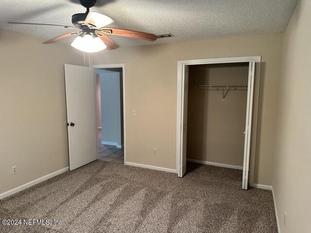 unfurnished bedroom featuring carpet flooring, a closet, ceiling fan, and a textured ceiling