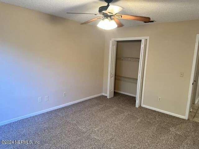 unfurnished bedroom with a textured ceiling, ceiling fan, a closet, and carpet floors