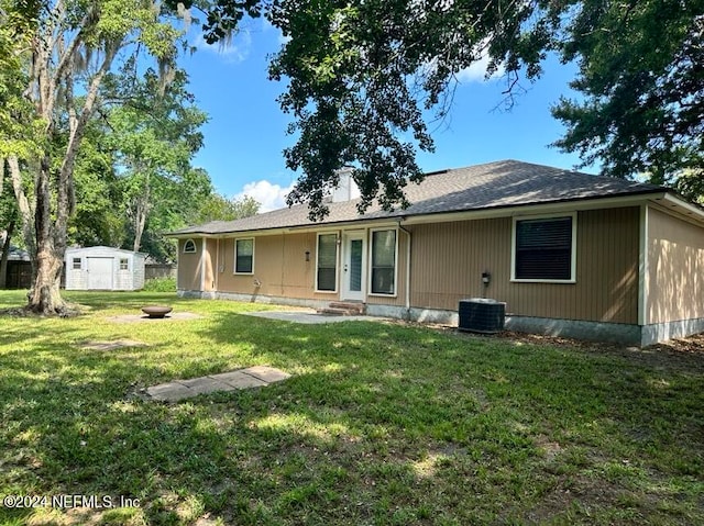 rear view of property featuring a yard and a storage unit