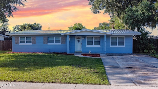 ranch-style house with metal roof, a front lawn, and fence