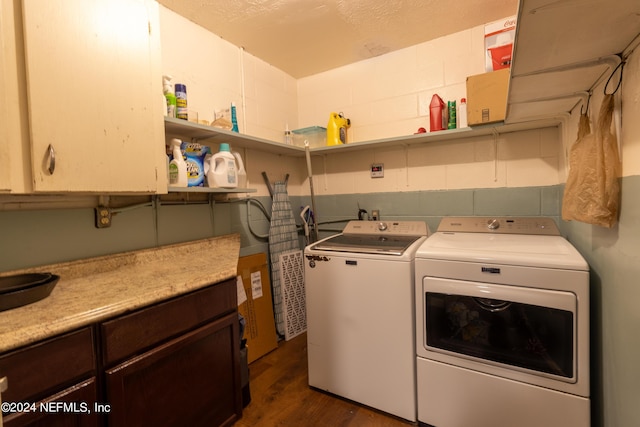 laundry room featuring dark wood finished floors, cabinet space, concrete block wall, and separate washer and dryer