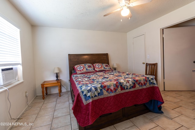 bedroom featuring a textured ceiling, cooling unit, light tile patterned floors, baseboards, and ceiling fan