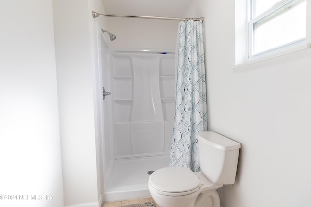 bathroom featuring toilet and a shower stall