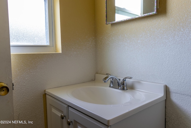 bathroom with vanity, plenty of natural light, and a textured wall