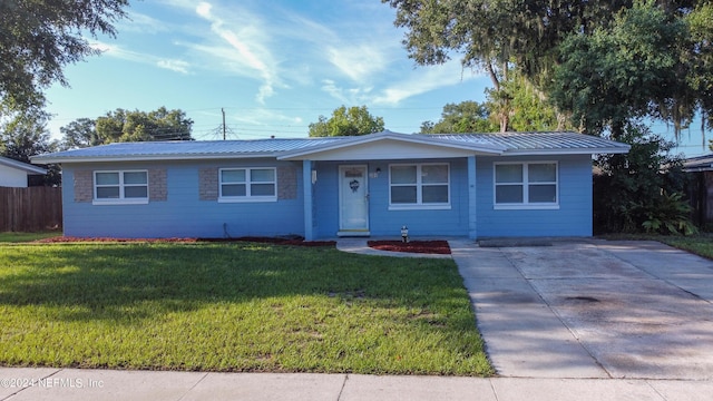 ranch-style house with metal roof, a front yard, and fence