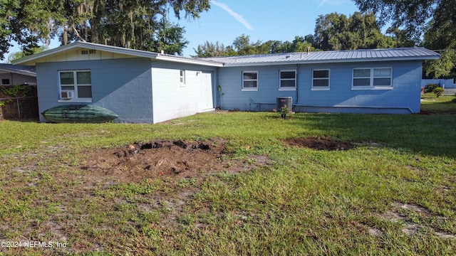 rear view of property featuring a yard, concrete block siding, cooling unit, and metal roof