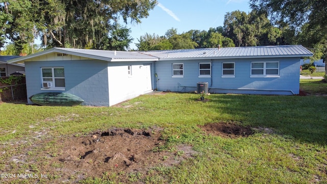 rear view of house with a yard, cooling unit, metal roof, and central AC