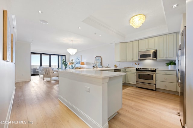 kitchen featuring a tray ceiling, stainless steel appliances, kitchen peninsula, a chandelier, and light wood-type flooring