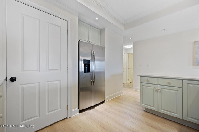 kitchen with light wood-type flooring, stainless steel fridge, and crown molding