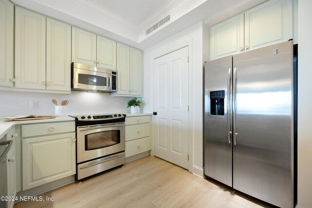 kitchen with ornamental molding, appliances with stainless steel finishes, and light hardwood / wood-style floors