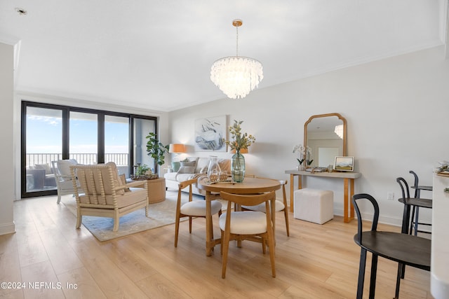 dining space with light wood-type flooring, a chandelier, and crown molding