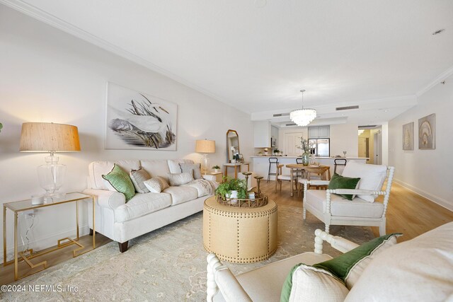 living room with hardwood / wood-style floors, a chandelier, and ornamental molding