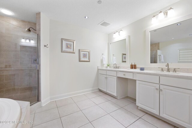 bathroom with vanity, a textured ceiling, plus walk in shower, and tile patterned floors