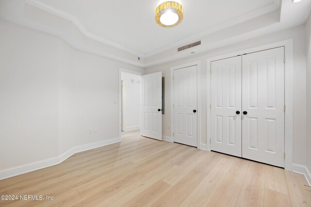 unfurnished bedroom with light hardwood / wood-style floors and multiple closets