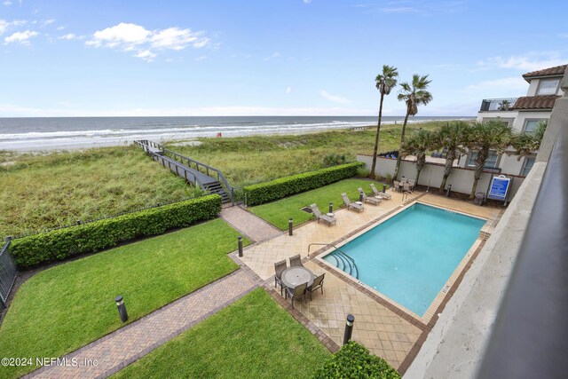 view of pool with a view of the beach, a lawn, a patio, and a water view