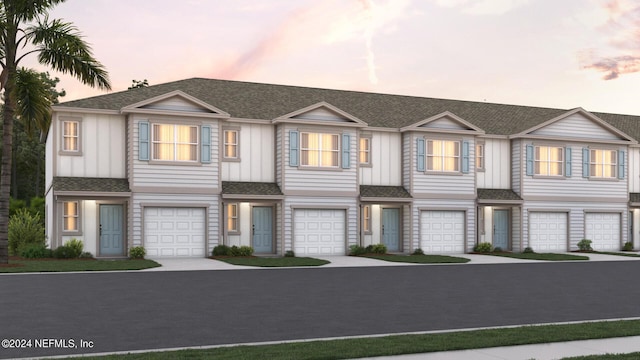 view of front of property featuring an attached garage, driveway, a shingled roof, and board and batten siding