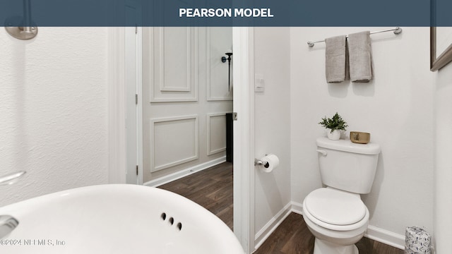 bathroom featuring a freestanding tub, baseboards, toilet, and wood finished floors