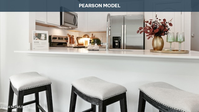 kitchen with stainless steel appliances, a breakfast bar, light countertops, and blue cabinetry