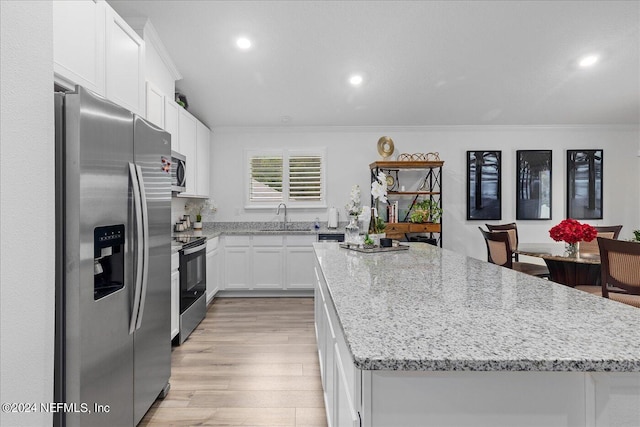 kitchen with a kitchen island, stainless steel appliances, light hardwood / wood-style flooring, and white cabinetry