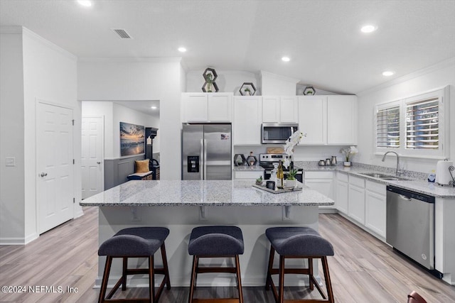 kitchen with vaulted ceiling, light stone countertops, a center island, stainless steel appliances, and sink