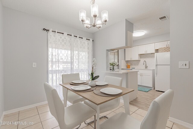 tiled dining area featuring a textured ceiling, a chandelier, and sink