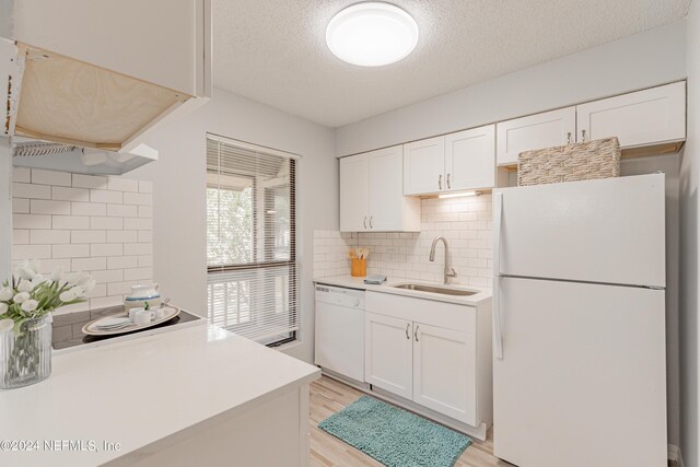 kitchen featuring white appliances, backsplash, sink, and white cabinets