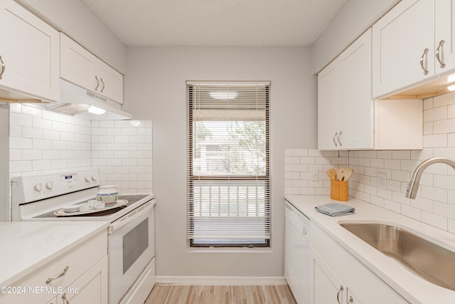 kitchen with white appliances, light hardwood / wood-style flooring, tasteful backsplash, sink, and white cabinetry