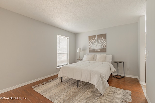 bedroom with a textured ceiling and dark hardwood / wood-style flooring