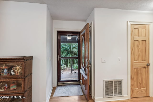 doorway featuring a textured ceiling and light hardwood / wood-style floors