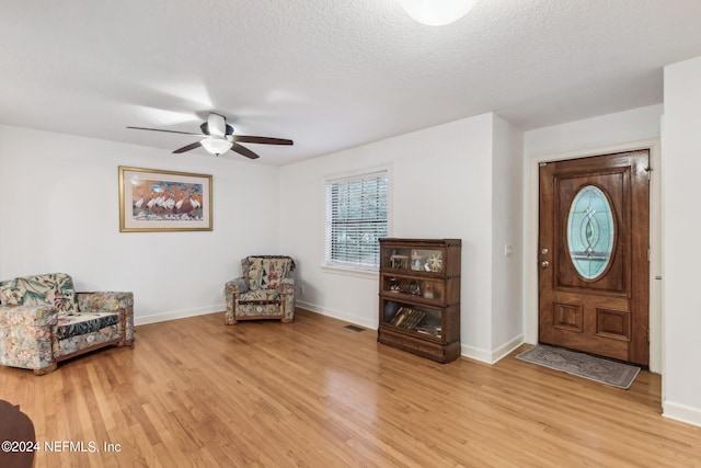 entryway with light wood-type flooring, ceiling fan, and a textured ceiling