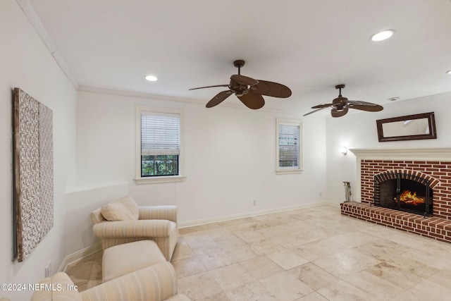 living area with ornamental molding, ceiling fan, and a brick fireplace