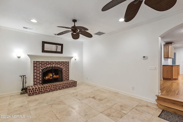 living room with ceiling fan, a brick fireplace, and crown molding