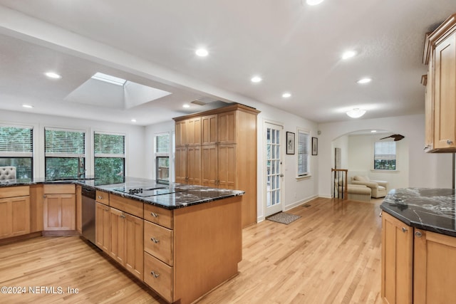 kitchen with kitchen peninsula, light hardwood / wood-style floors, a skylight, and dishwasher