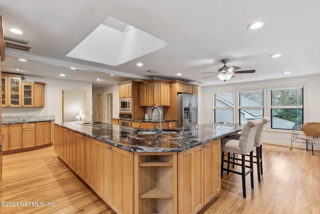 kitchen with appliances with stainless steel finishes, light hardwood / wood-style floors, a large island, and sink