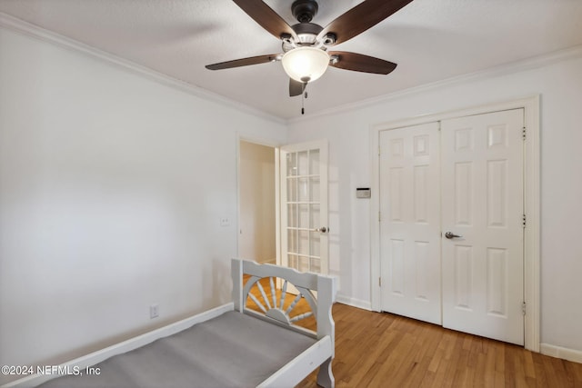 unfurnished bedroom with a closet, light hardwood / wood-style floors, ceiling fan, and crown molding