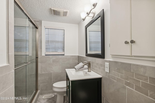 bathroom featuring a textured ceiling, walk in shower, vanity, and toilet