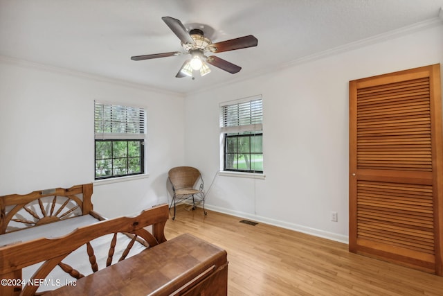 living area with light wood-type flooring, ornamental molding, and ceiling fan