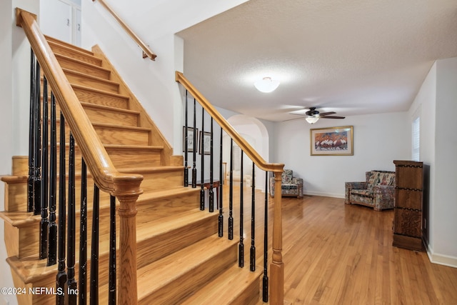 stairway with wood-type flooring and a textured ceiling