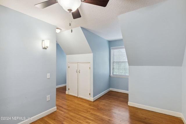 additional living space with ceiling fan, a textured ceiling, light hardwood / wood-style flooring, and vaulted ceiling