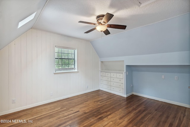 bonus room with a textured ceiling, dark hardwood / wood-style floors, vaulted ceiling, wood walls, and ceiling fan