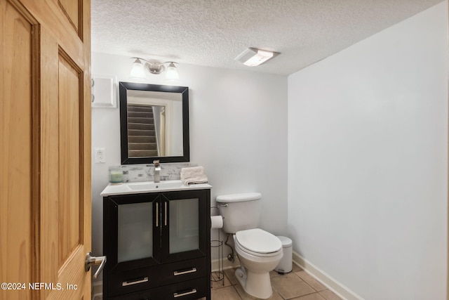 bathroom with vanity, toilet, a textured ceiling, and tile patterned floors