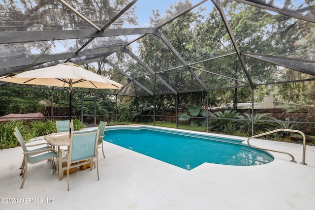 view of pool with glass enclosure and a patio area