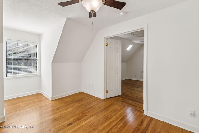 bonus room featuring a textured ceiling, baseboards, and light wood-style floors