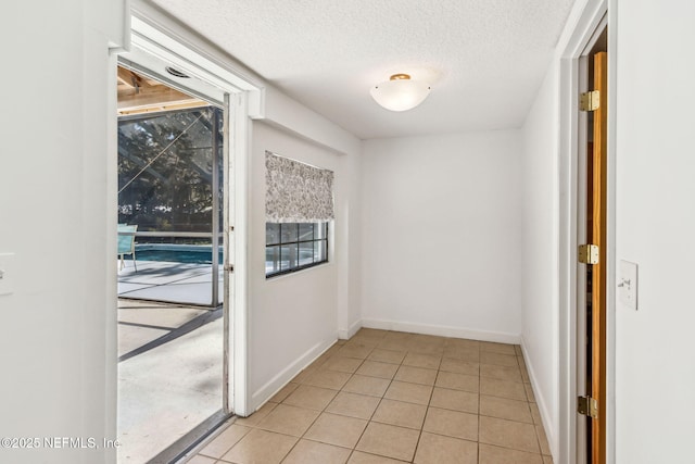 interior space with a textured ceiling, baseboards, and light tile patterned floors