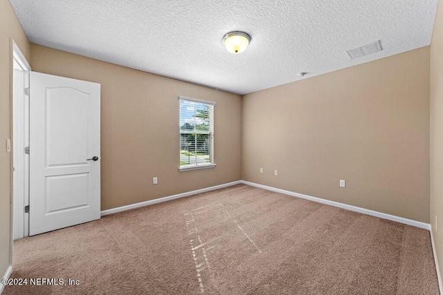 carpeted empty room featuring a textured ceiling