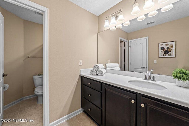 bathroom featuring vanity, toilet, tile patterned floors, and a textured ceiling