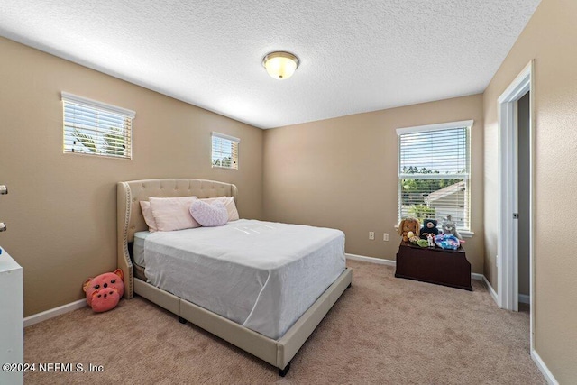 carpeted bedroom with a textured ceiling and multiple windows