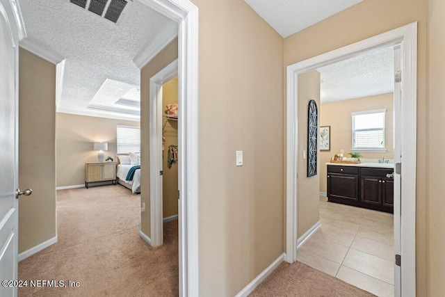 corridor featuring a textured ceiling, sink, and light carpet