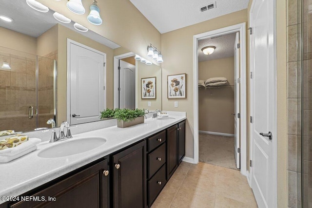 bathroom featuring tile patterned floors, a shower with door, a textured ceiling, and vanity