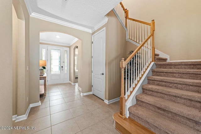 entryway featuring ornamental molding, a textured ceiling, and light tile patterned floors